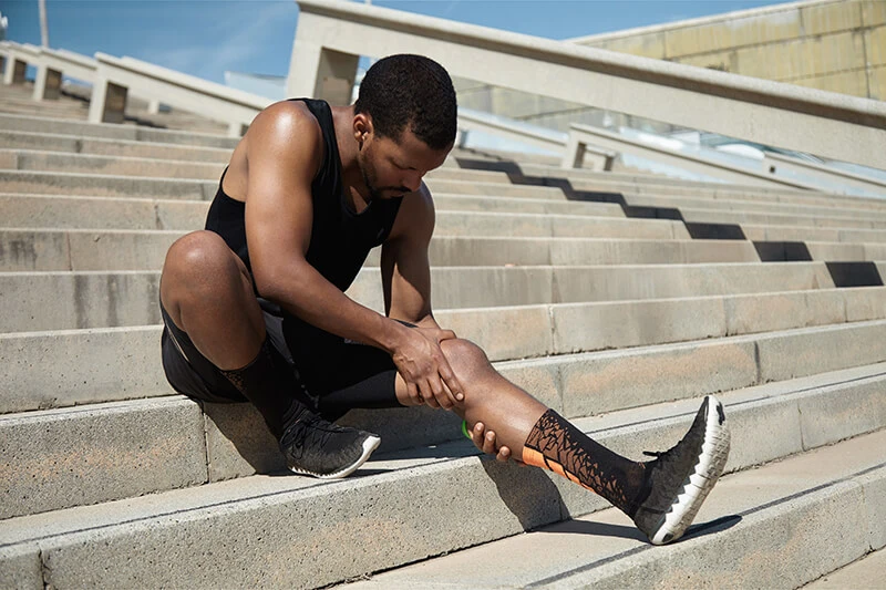 An athlete sitting on stairs suffering from a sports injury