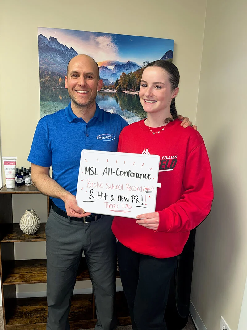 Dr. Nate Porcher, chiropractor Arlington Heights, posing with a patient holding a sign at his clinic